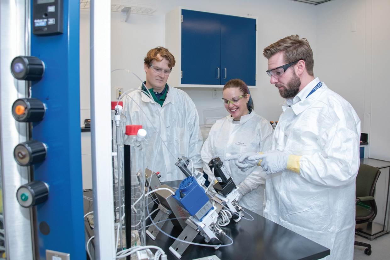 Three scientists working on equipment in a lab