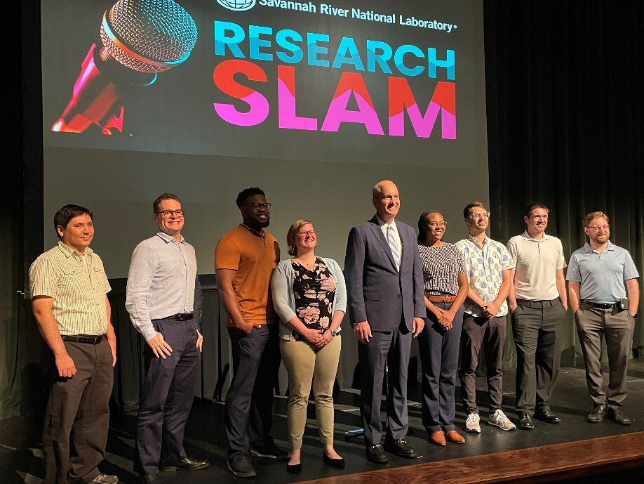 Participants of the SRNL Research SLAM standing onstage and smiling.