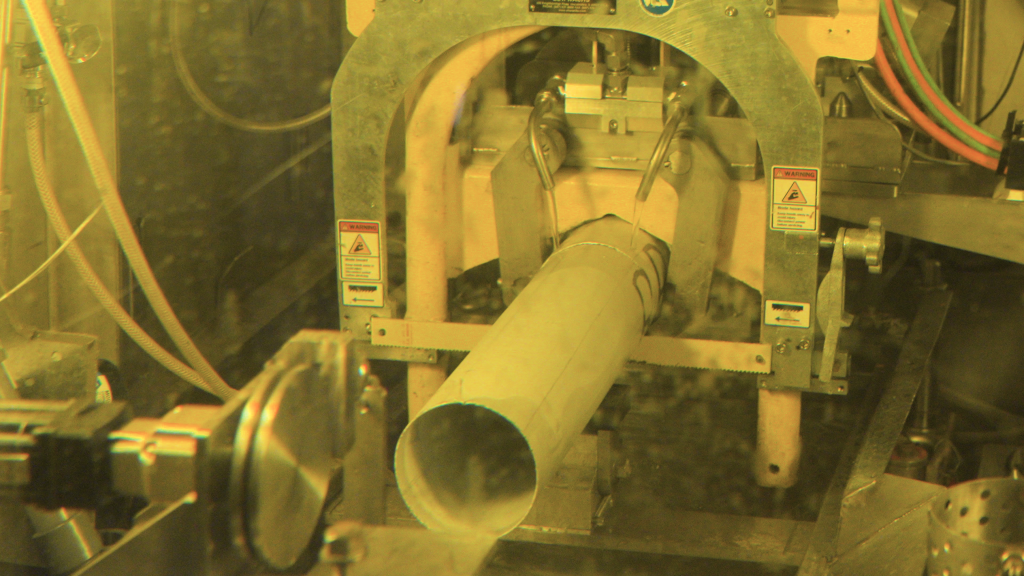 Image of a machine cutting a cylindrical object inside a 3-foot-thick leaded glass window.