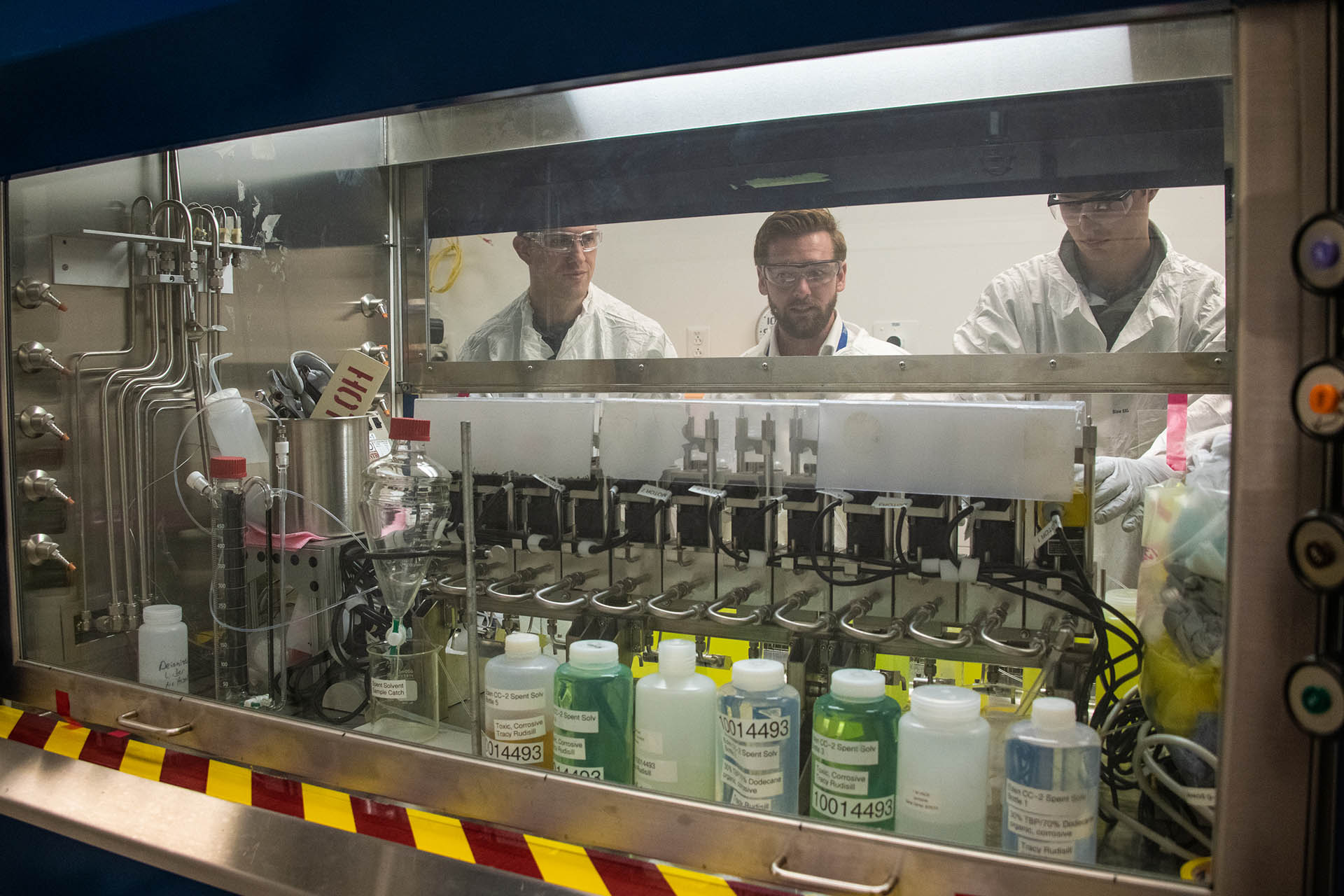 scientists looking into a chemical hood filled with bottles