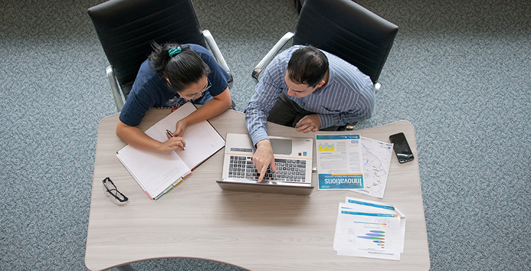 Overhead view of two people sitting at a desk working