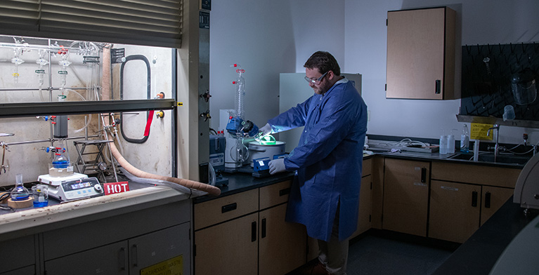 A man wearing safety glasses and gloves working in a lab