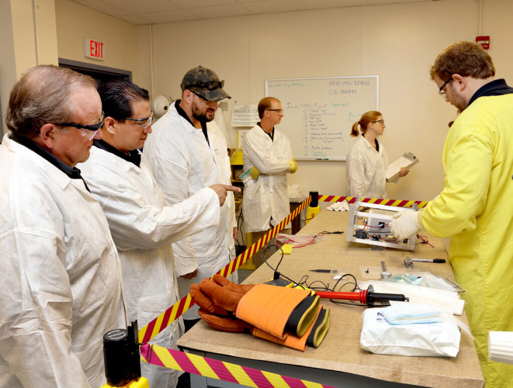 scientists standing at a table surrounded by radioactive caution tape