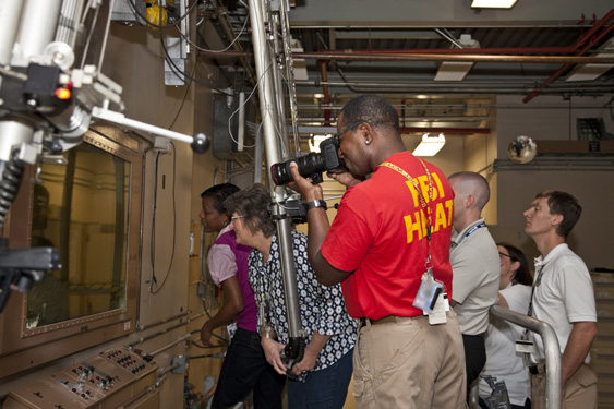 A man taking pictures, group of people looking through plexiglass