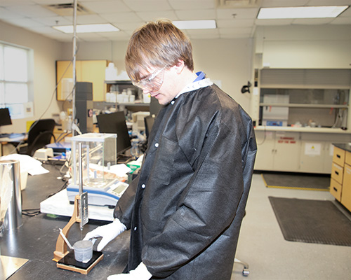 women in hairnet and mask pipetting into test tube