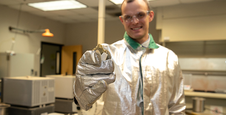 Scientist holding piece of grout in gloved hand